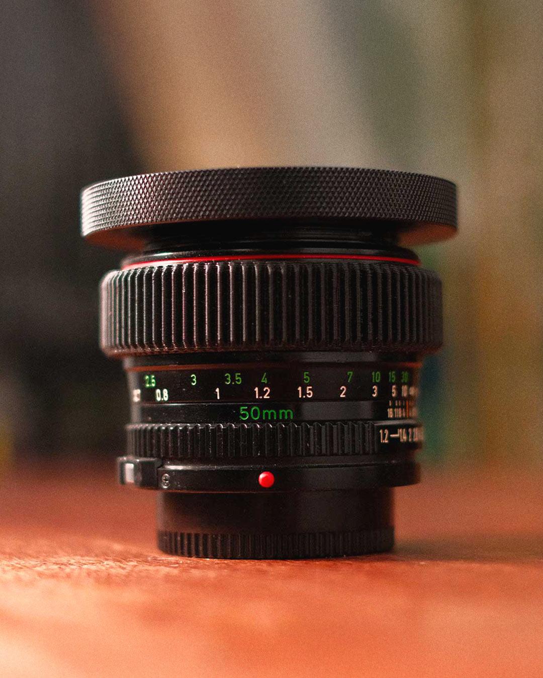 Objectif Canon FD L 50mm posé sur une table en lumière douce, illustrant son utilisation en vidéo et cinéma sur le blog de Robin WHR.