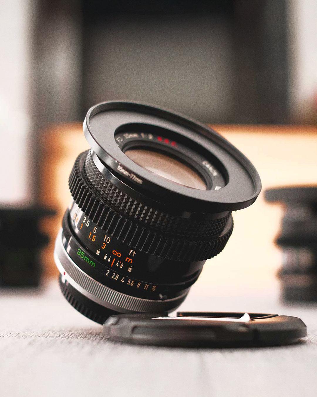 Objectif Canon FD 35mm argentique posé sur une table, utilisé pour les vidéos cinéma de Robin WHR, illustrant le look vintage et la qualité d'image en tournage.