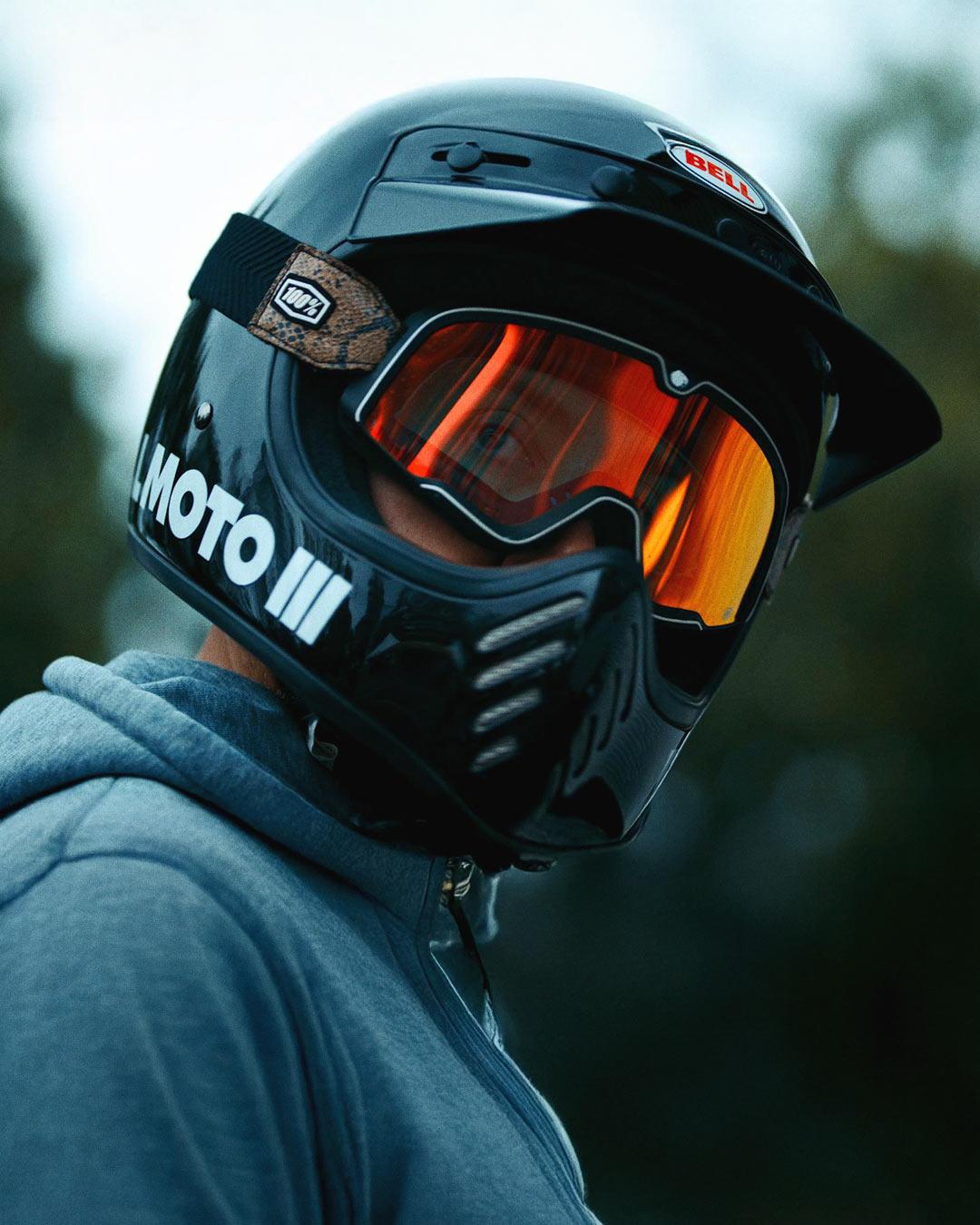 Portrait d'un motard avec casque et lunettes oranges filmé au téléobjectif, illustrant l'utilisation des longues focales en vidéo professionnelle.