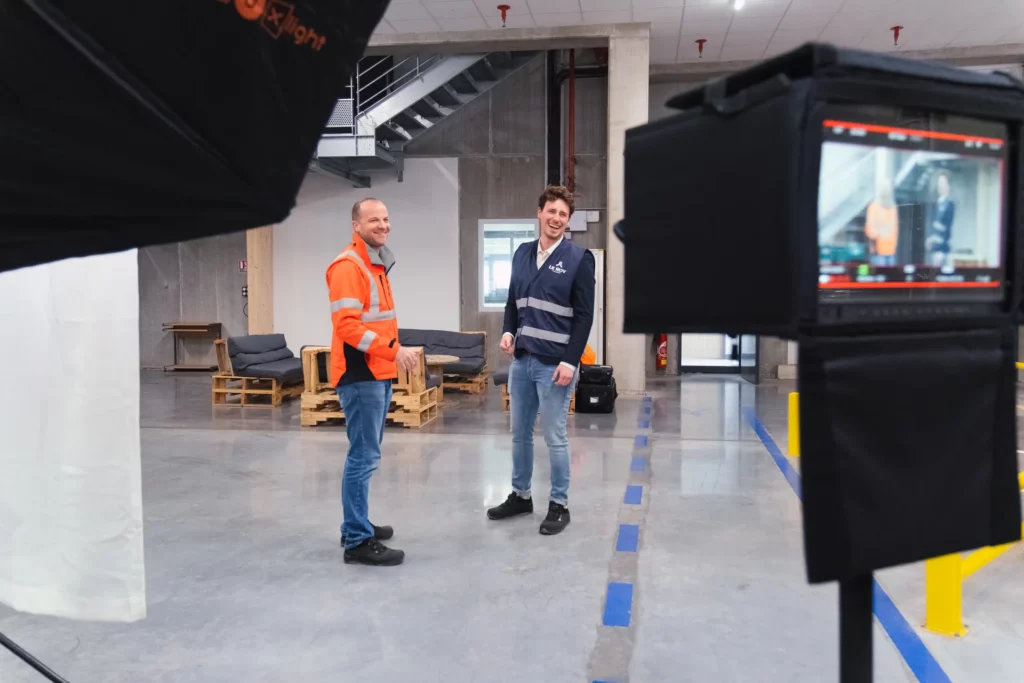Équipe suivant une scène sur un moniteur pendant le tournage du film dans un espace logistique.