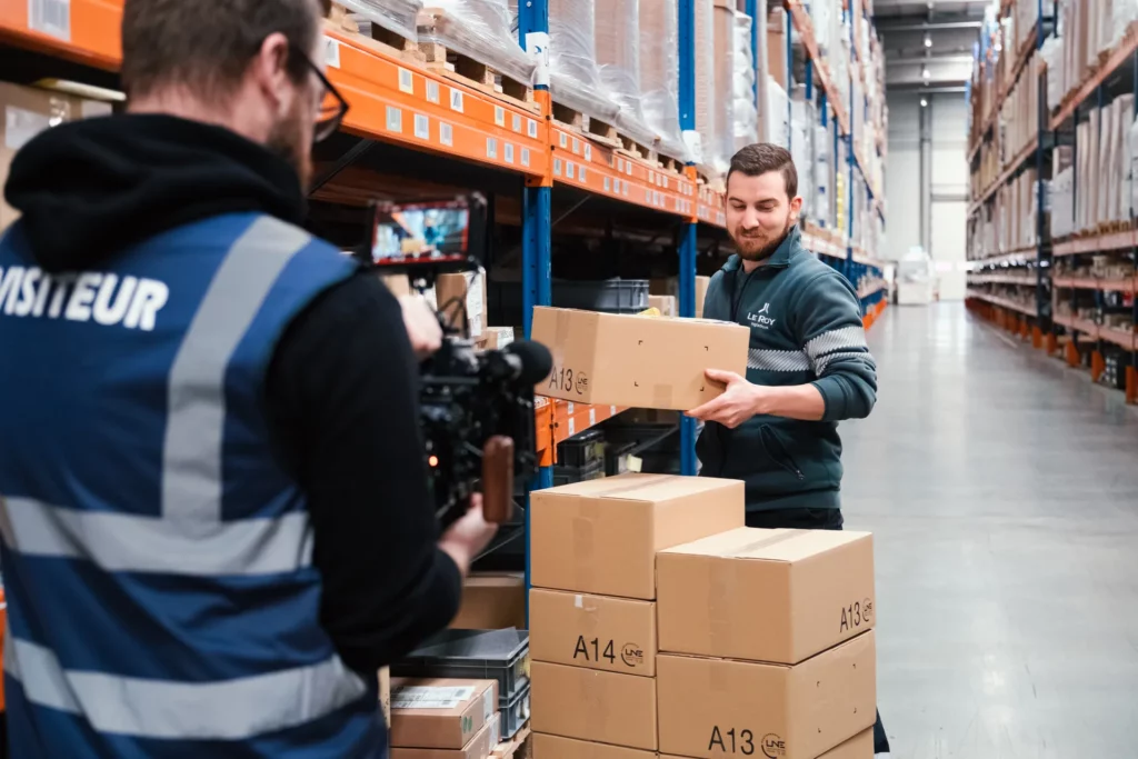Tournage d’un collaborateur manipulant des cartons dans une allée de l’entrepôt Le Roy Logistique.