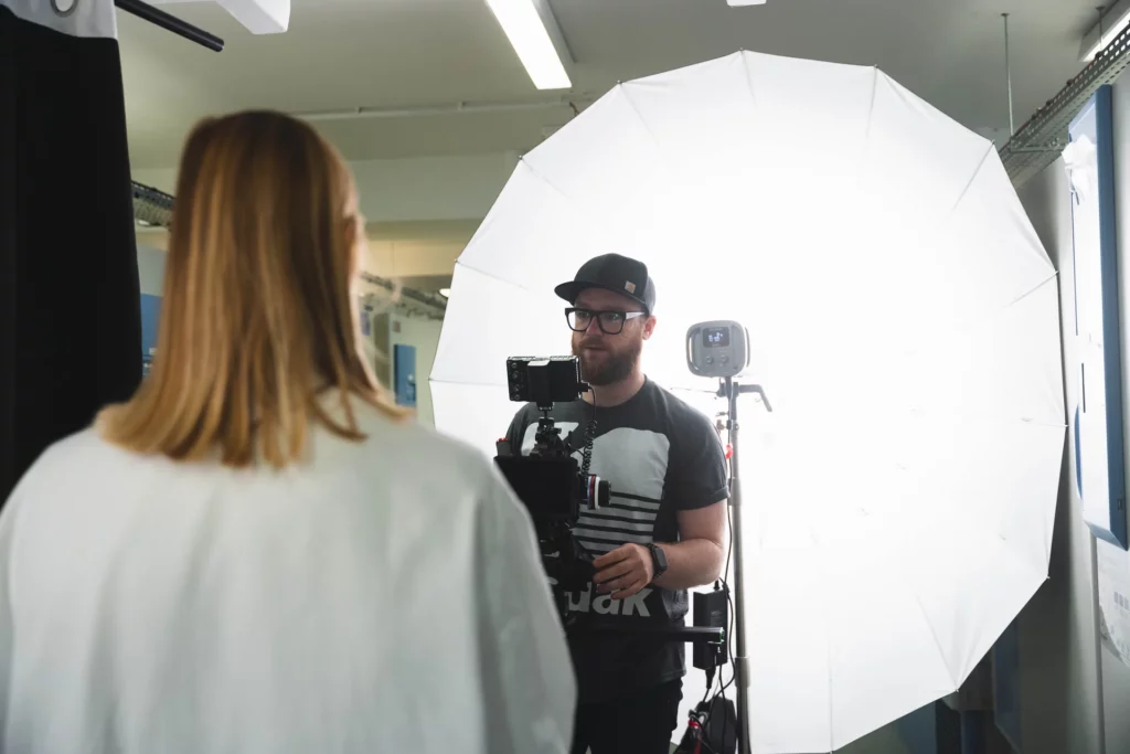 Chef opérateur filmant une chercheuse avec un grand diffuseur blanc pendant une interview.