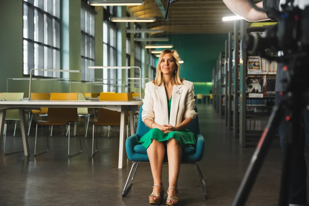 Scientifique installée face à la caméra pour une interview dans un espace universitaire.