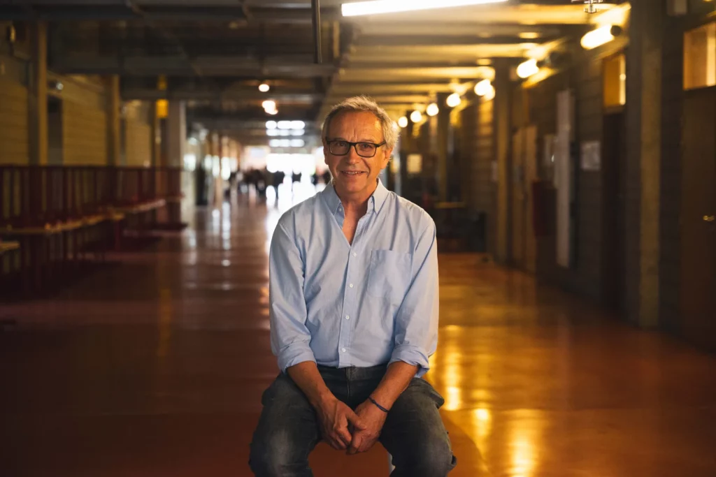 Portrait d’un chercheur assis dans un couloir universitaire pendant le tournage.