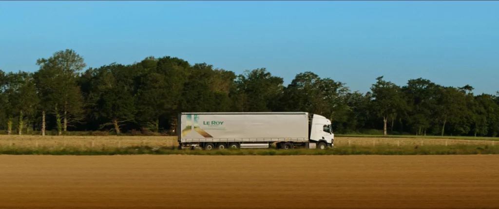 Camion Le Roy Logistique roulant sur une route de campagne bordée de champs et d’arbres.
