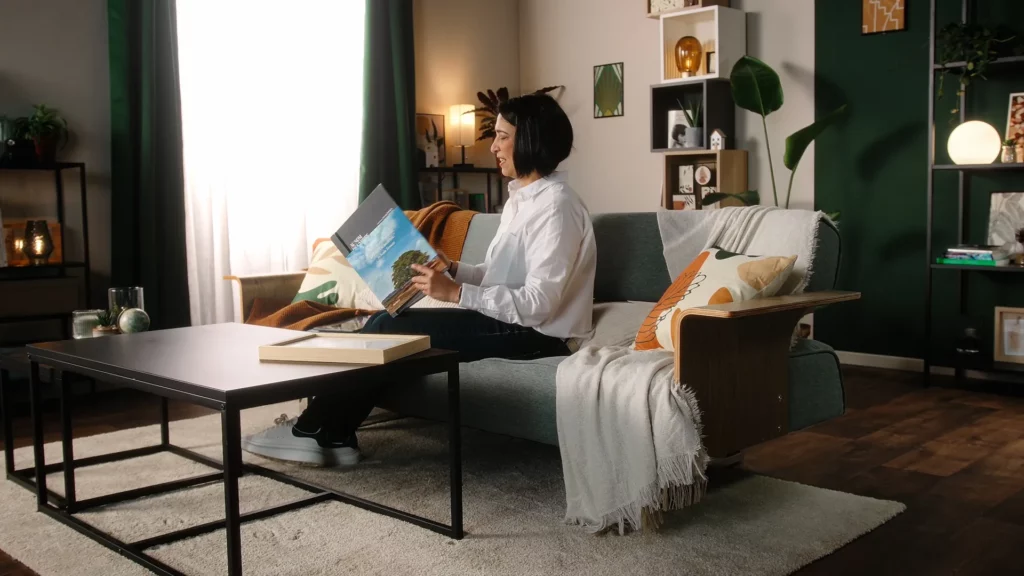 Lauréate du prix Biodiversiday assise dans un décor salon lumineux, un livret ouvert entre les mains.
