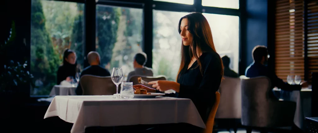 Cliente assise à une table de restaurant devant une assiette de crêpe, dans une ambiance élégante et chaleureuse.
