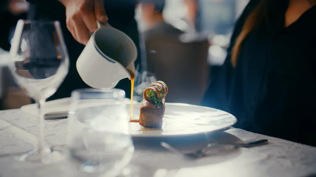 Main versant une boisson chaude à table pendant une dégustation dans un restaurant lumineux.
