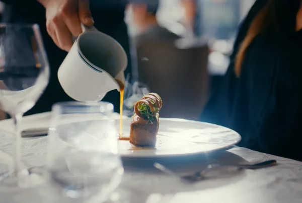 Main versant une boisson chaude à table pendant une dégustation dans un restaurant lumineux.