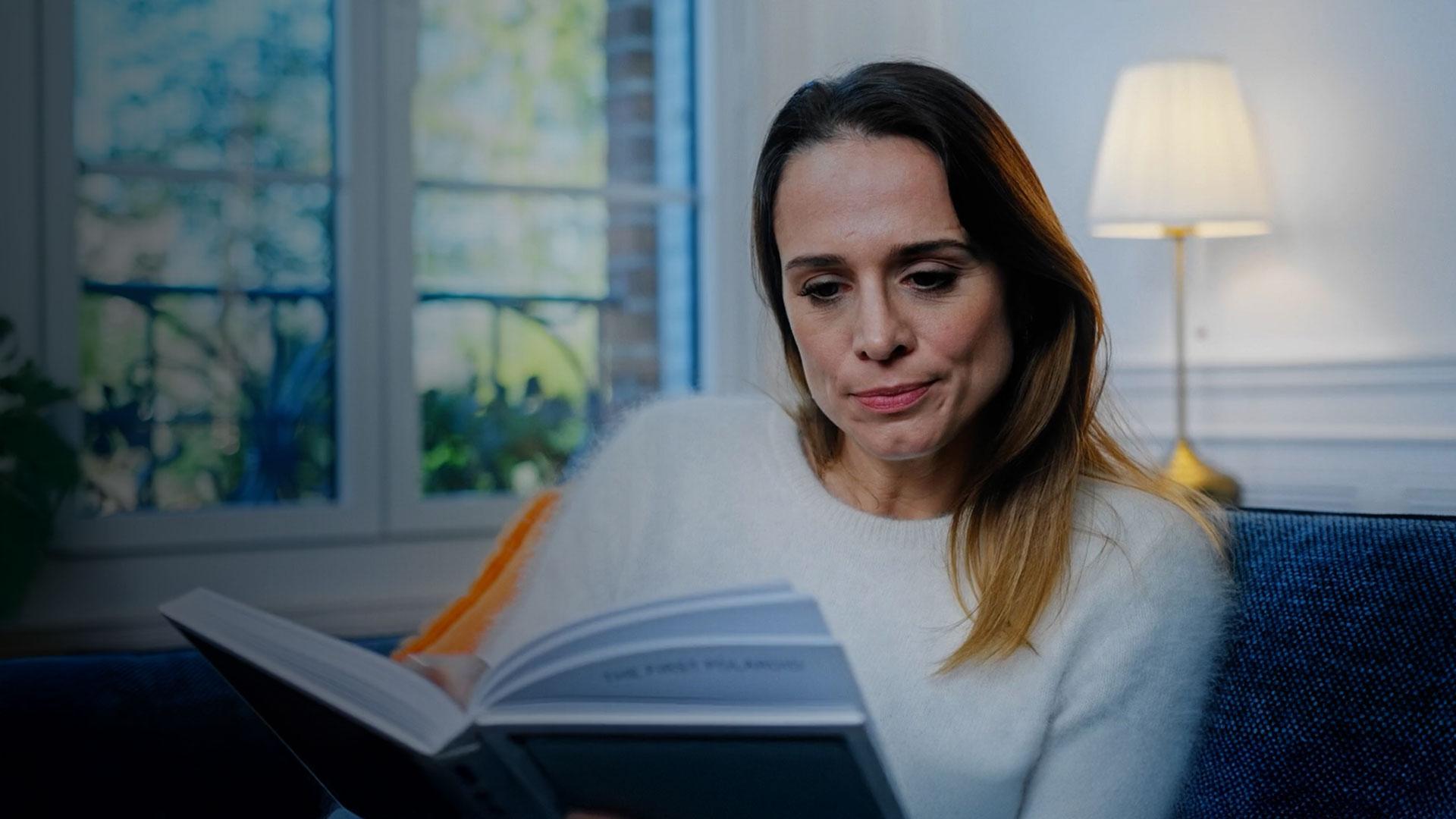 Portrait d'une femme lisant un livre dans un salon lumineux pour une publicité Nissan