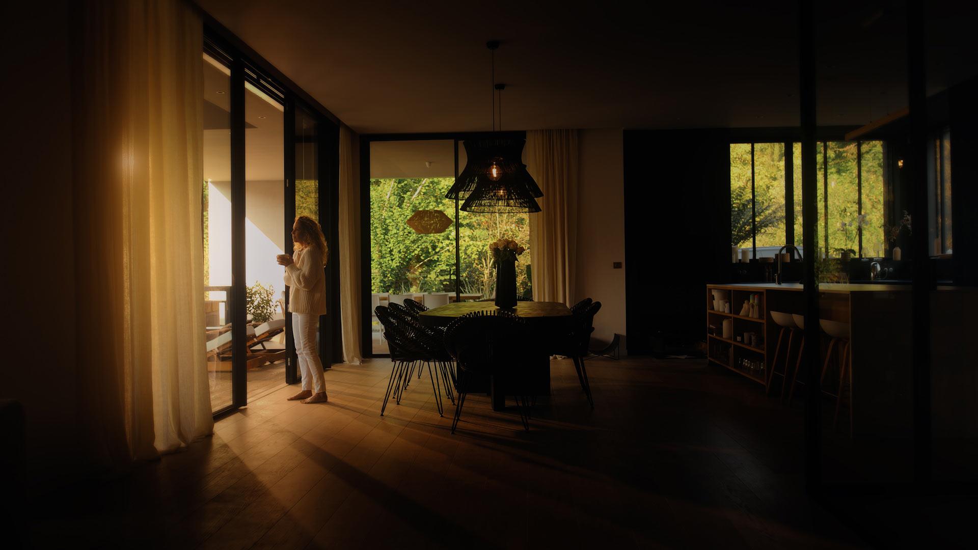 Vue intérieure d’un salon baigné de lumière chaude traversant de grandes baies vitrées, créant une atmosphère de confort et de cocon.