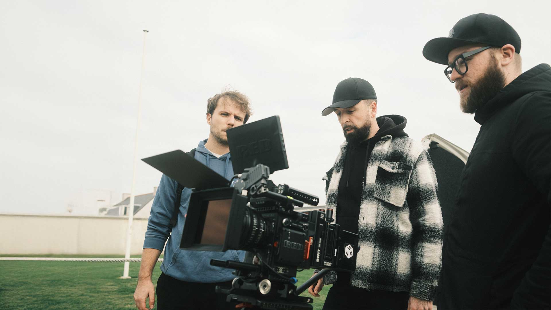 Trois membres de l’équipe de tournage concentrés sur un retour caméra – Robin Welschinger