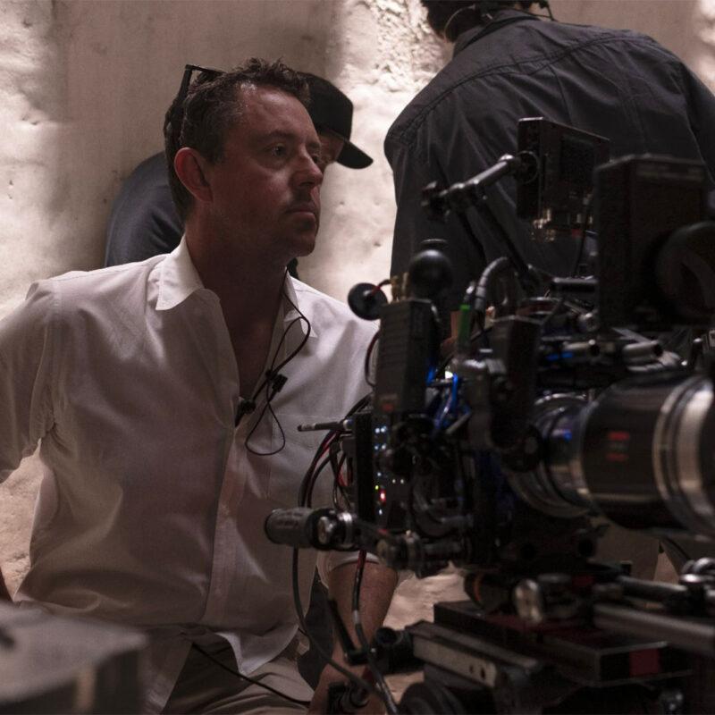 Greig Fraser sur un plateau de tournage, concentré derrière une caméra cinéma, illustrant son approche sensible de la mise en scène au-delà de la lumière