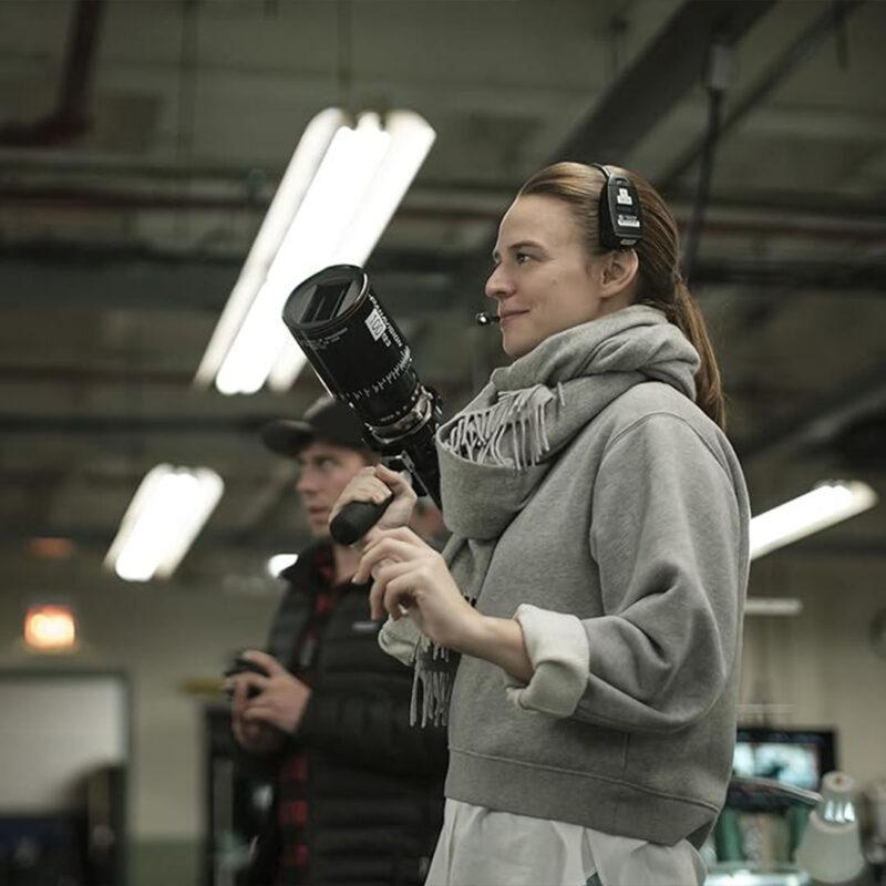 Jessica Lee Gagné sur un plateau de tournage, tenant une caméra avec casque et talkie, directrice de la photographie devenue réalisatrice sur la série Severance