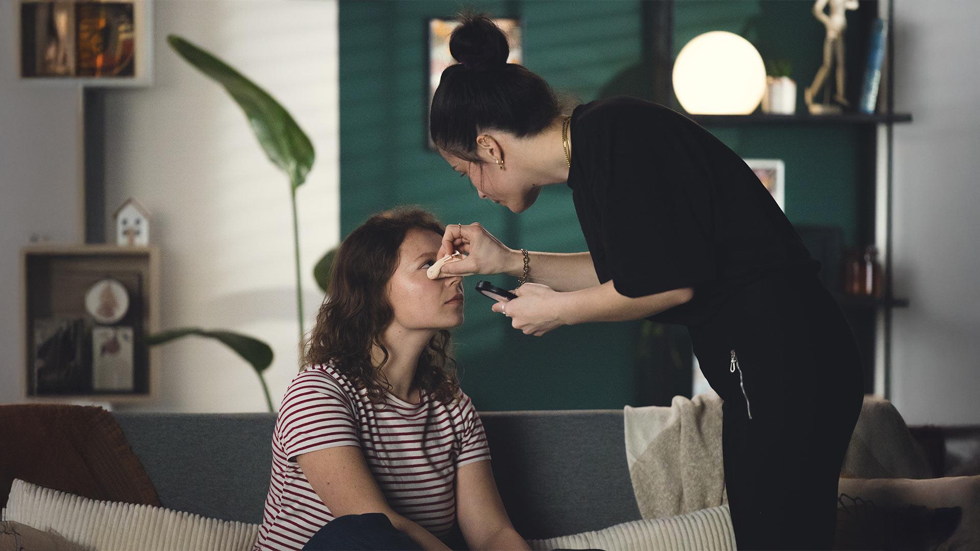 Maquilleuse retouchant le teint d’une comédienne sur un tournage vidéo dirigé par Robin Welschinger