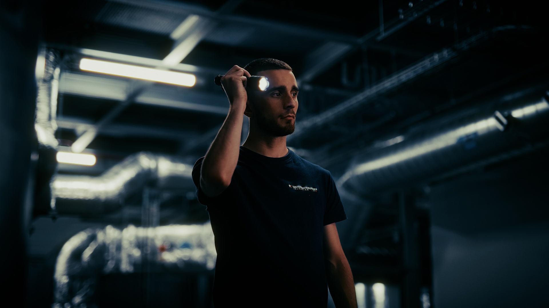 Portrait d’un technicien Panpharma dans l’usine, éclairé à la lampe torche dans une ambiance sombre et graphique