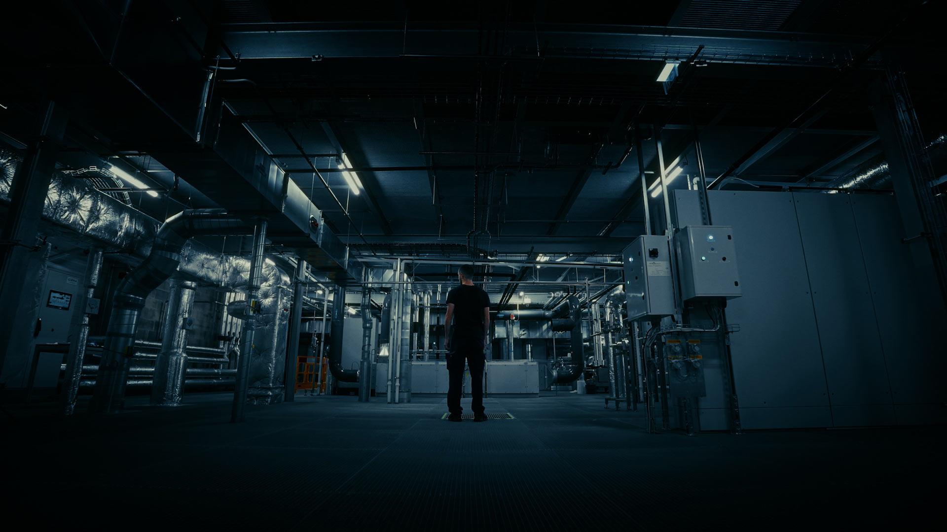 Technicien Panpharma debout au centre d’une vaste zone industrielle, éclairage dirigé et ambiance futuriste