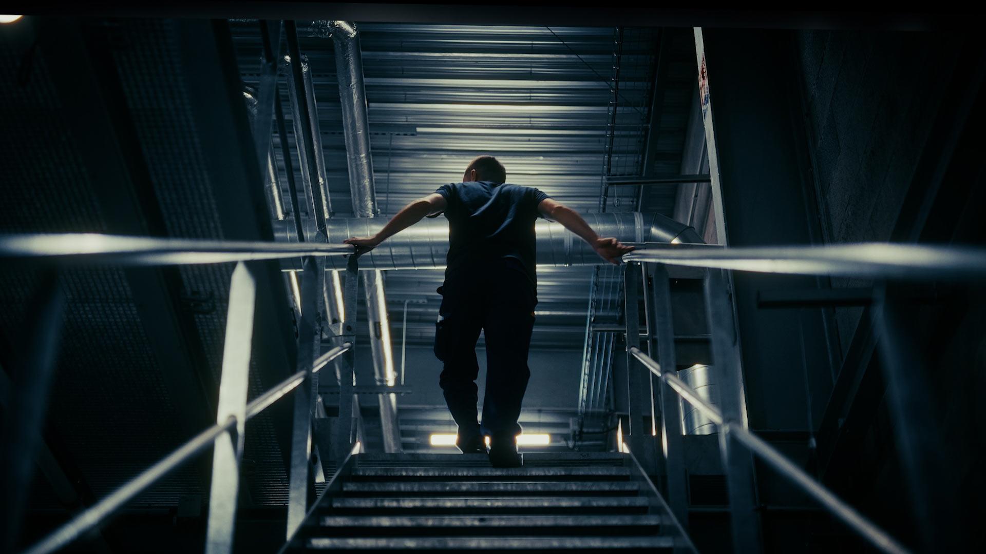 Technicien Panpharma montant un escalier métallique au milieu des conduits et machines, style vaisseau spatial