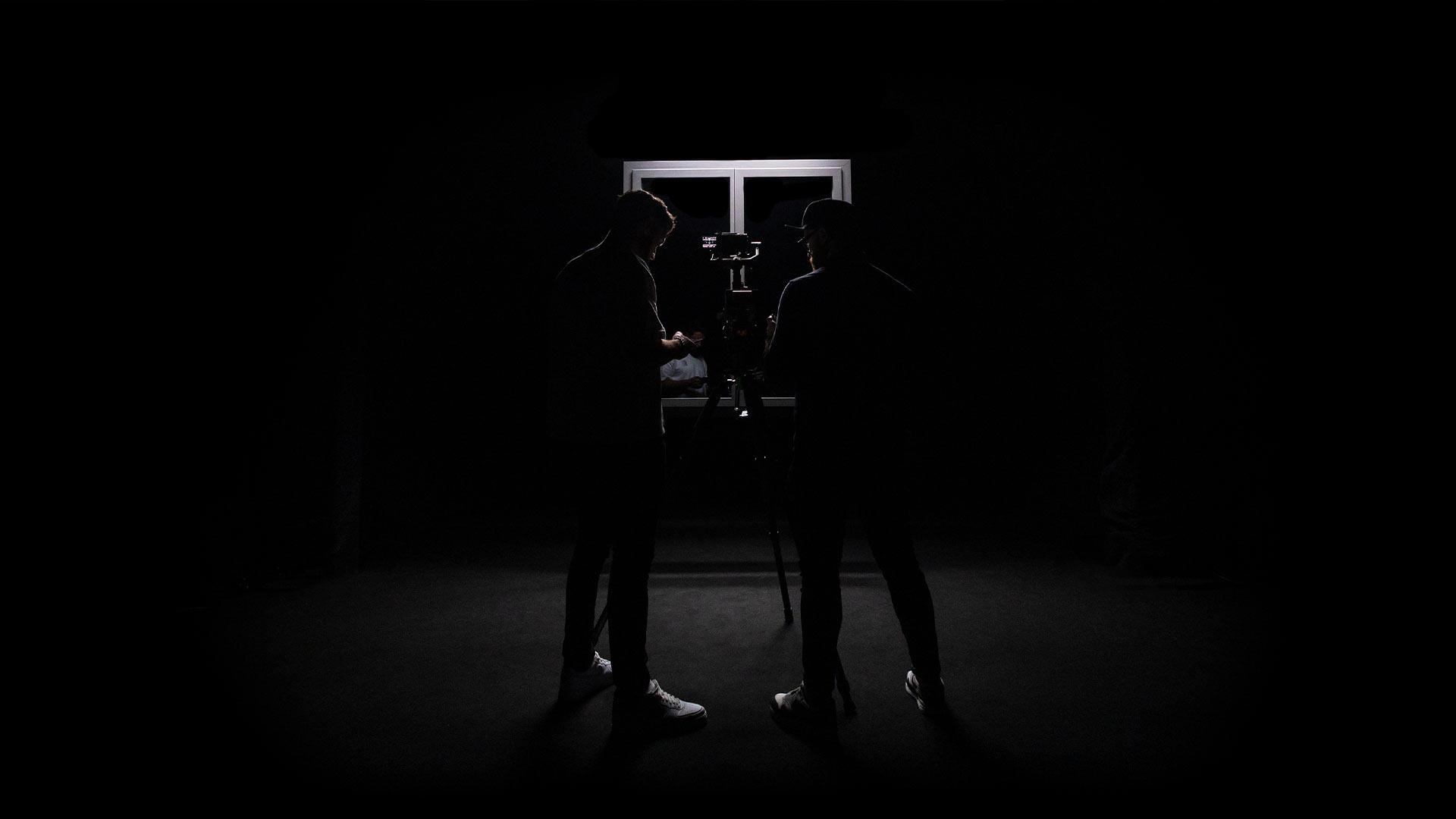 Deux silhouettes d'un réalisateur et chef opérateur en contre-jour devant une caméra, lumière noire dramatique – Robin Welschinger chef opérateur et réalisateur