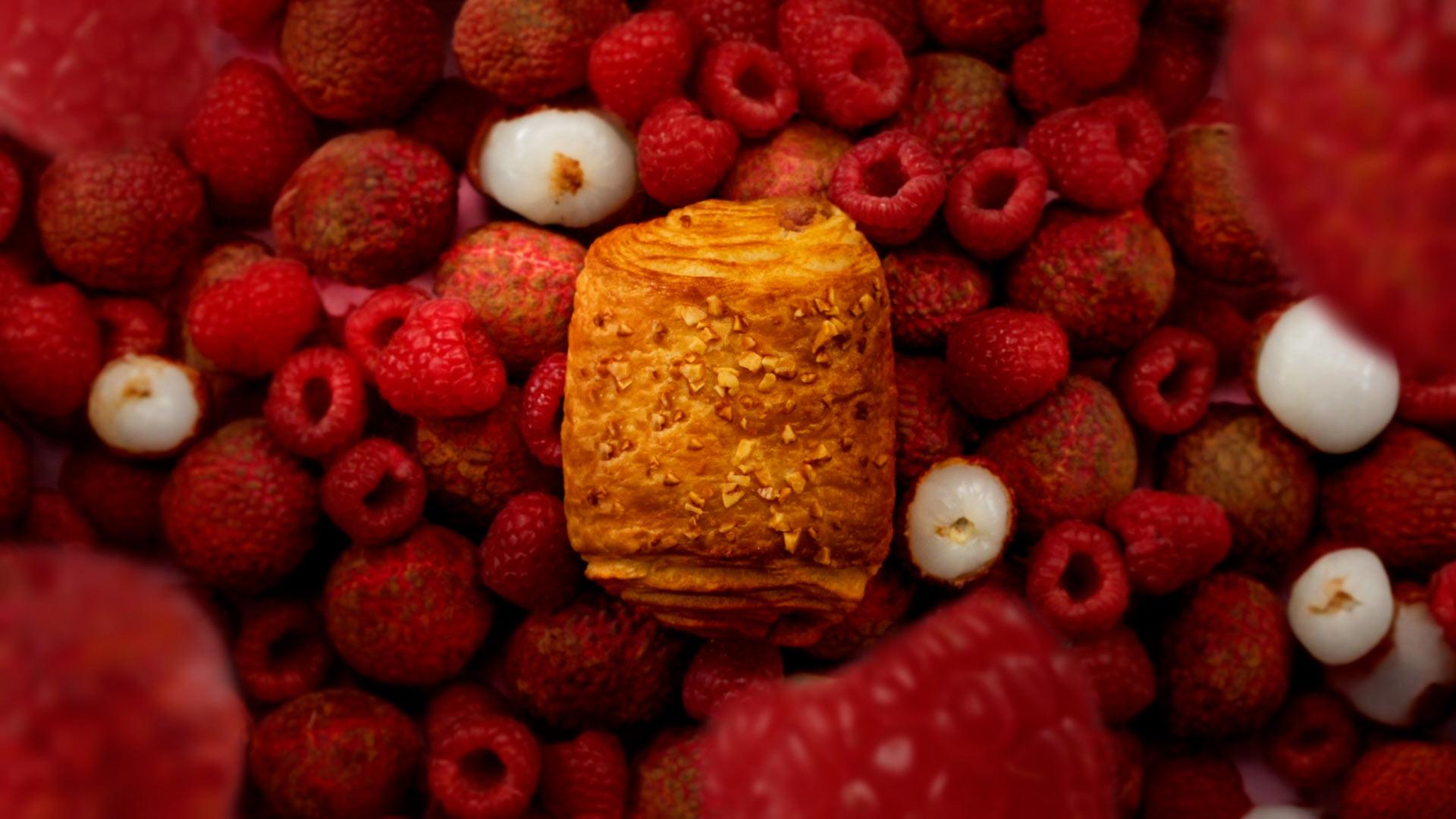 Vue en plongée du feuilleté Signature framboise litchi entouré de fruits, pour la vidéo de lancement Bridor x Pierre Hermé Paris