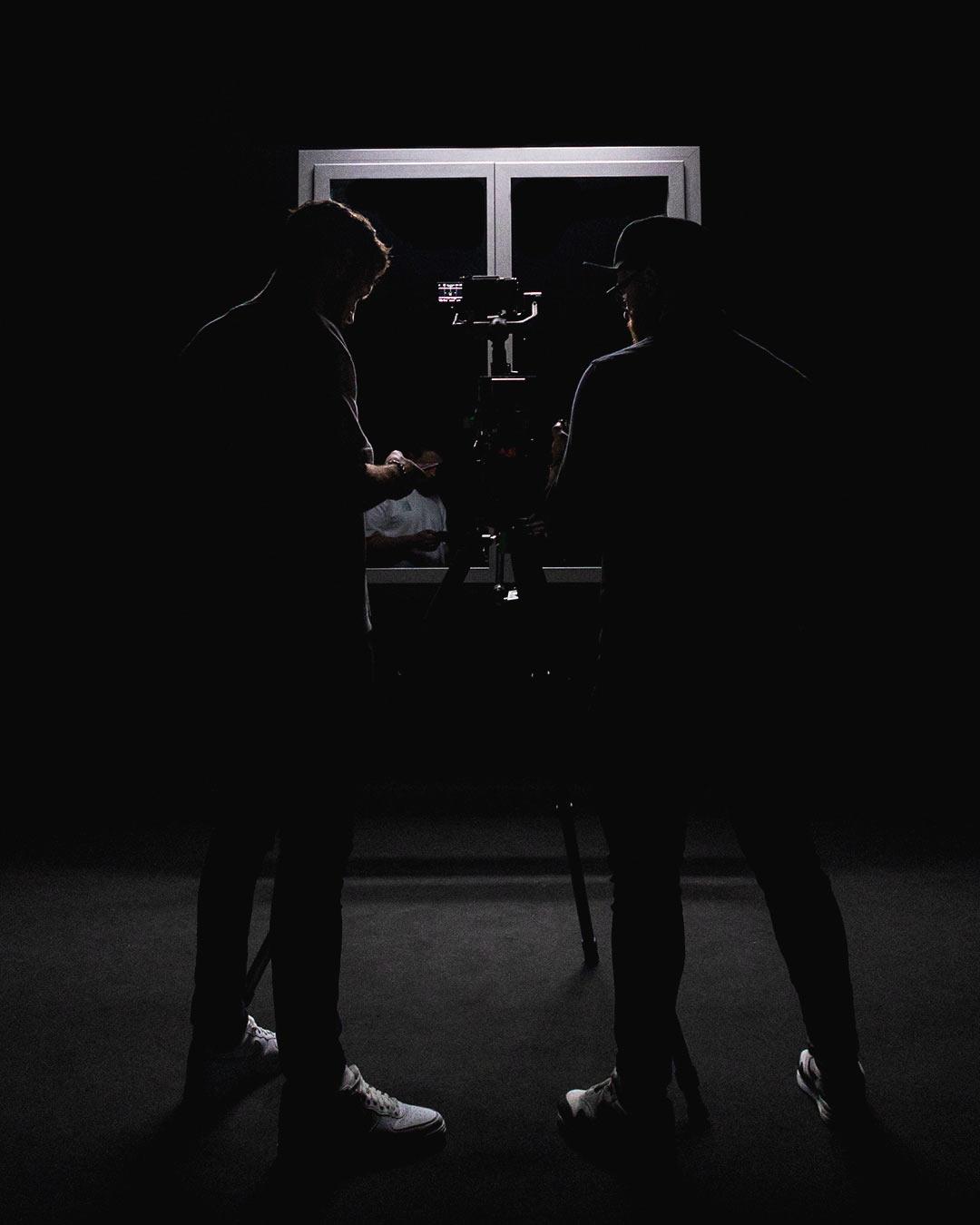 Silhouettes de deux vidéastes devant une caméra en contre-jour, illustrant la dualité entre réalisation et image