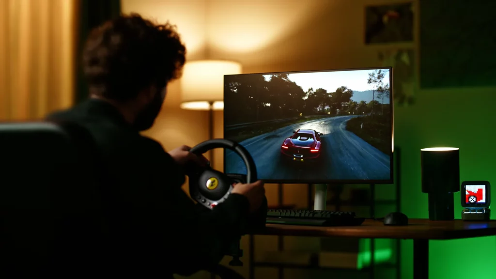 Joueur utilisant un volant Thrustmaster T98 face à un écran affichant une course automobile.