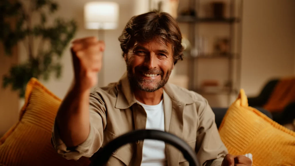 Joueur levant le poing après une course au volant Thrustmaster T98 dans un salon chaleureux.