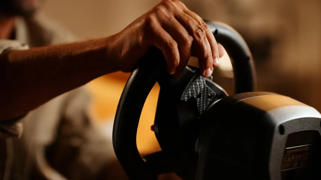 Main d’un joueur saisissant le volant gaming Thrustmaster T98 dans une lumière chaude et immersive.