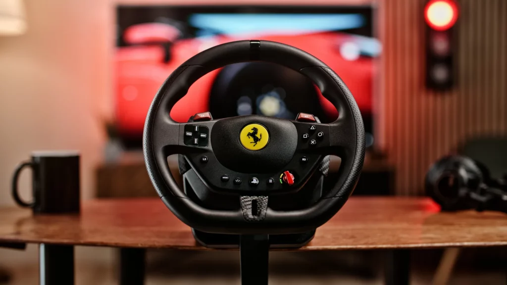 Volant gaming Thrustmaster T98 sous licence Ferrari présenté sur une table devant un écran de course.