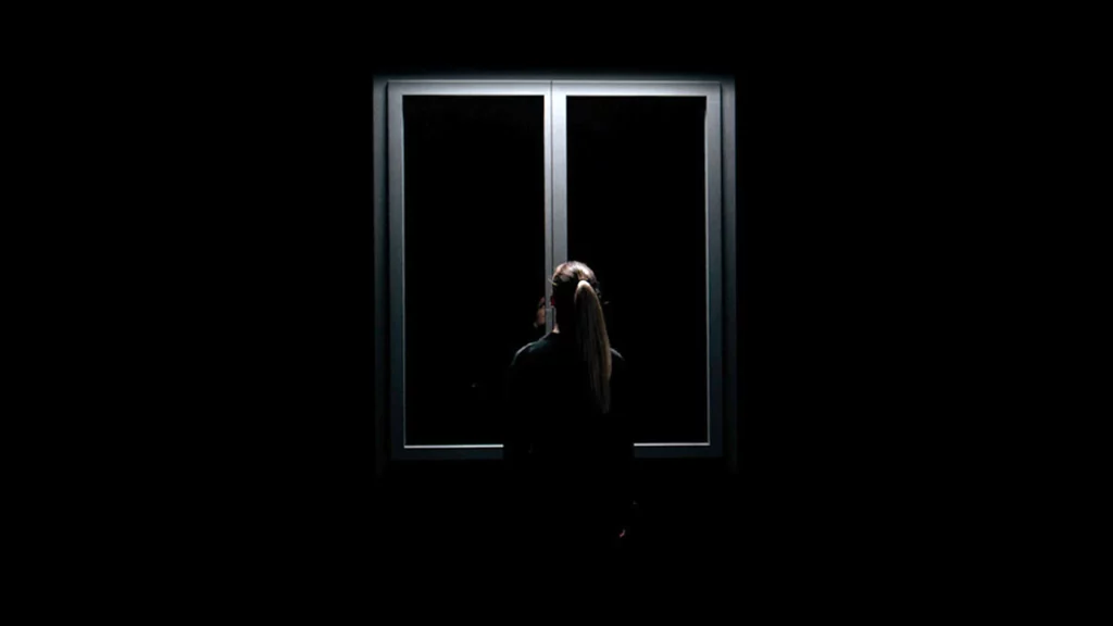 Modèle de dos devant une fenêtre premium Bochassy dans une mise en scène studio noire et minimaliste.