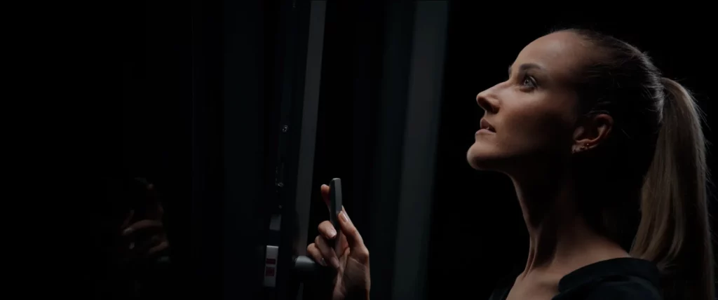 Profil d’un modèle tenant la poignée d’une fenêtre premium Bochassy dans une lumière de studio précise.