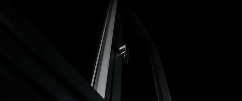 Poignée de fenêtre Bochassy vue en contre-plongée, mise en valeur par une lumière graphique sur fond noir.