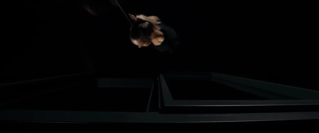 Vue en plongée d’un modèle se penchant sur une fenêtre Bochassy ouverte dans un univers studio sombre.