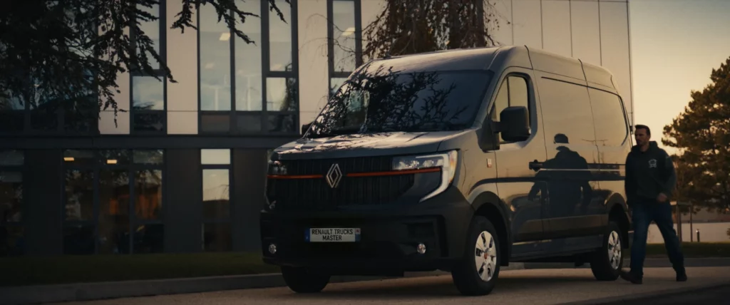 Un véhicule utilitaire Renault stationné devant un bâtiment au coucher du soleil.