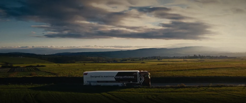 Un camion Renault Trucks roule sur une route de campagne au coucher du soleil.