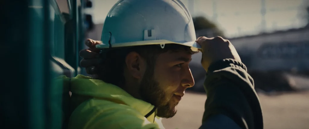 Un professionnel en gilet haute visibilité ajuste son casque de chantier.