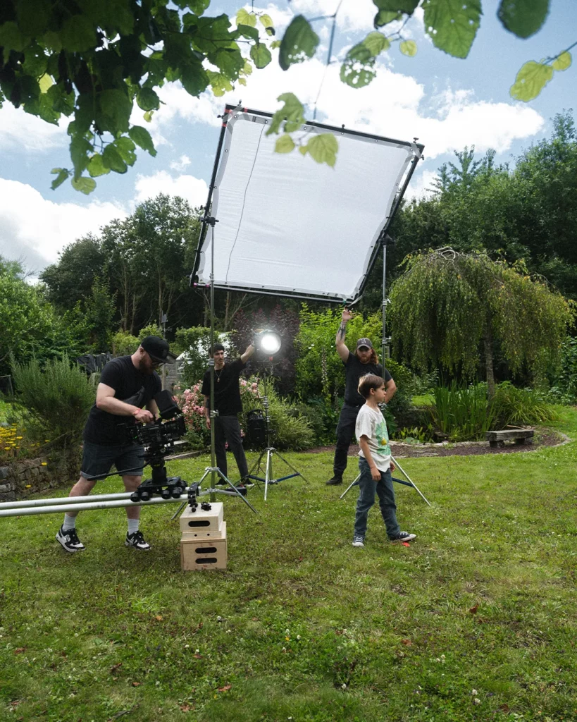 about-bts-dispositif-lumiere-tournage-exterieur Dispositif de lumière diffusée installé en extérieur pour filmer une scène dans un jardin.
