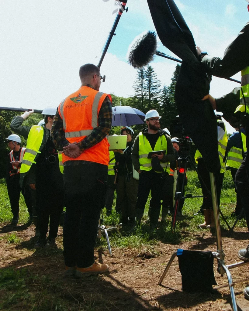 about-bts-equipe-tournage-exterieur-gilets Équipe de tournage en extérieur avec techniciens en gilets de sécurité autour du dispositif caméra.