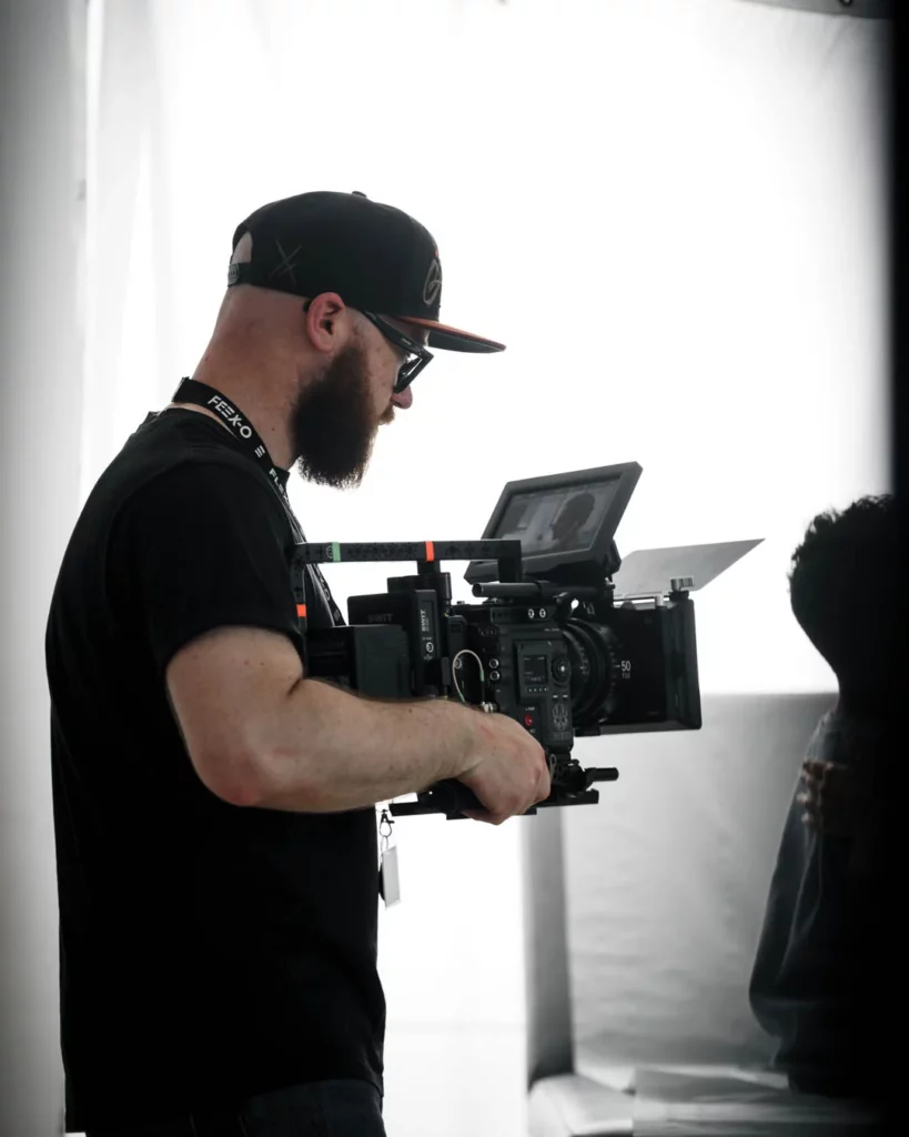 about-bts-operateur-camera-interieur Opérateur tenant une caméra cinéma dans un intérieur pendant la préparation d’une prise.