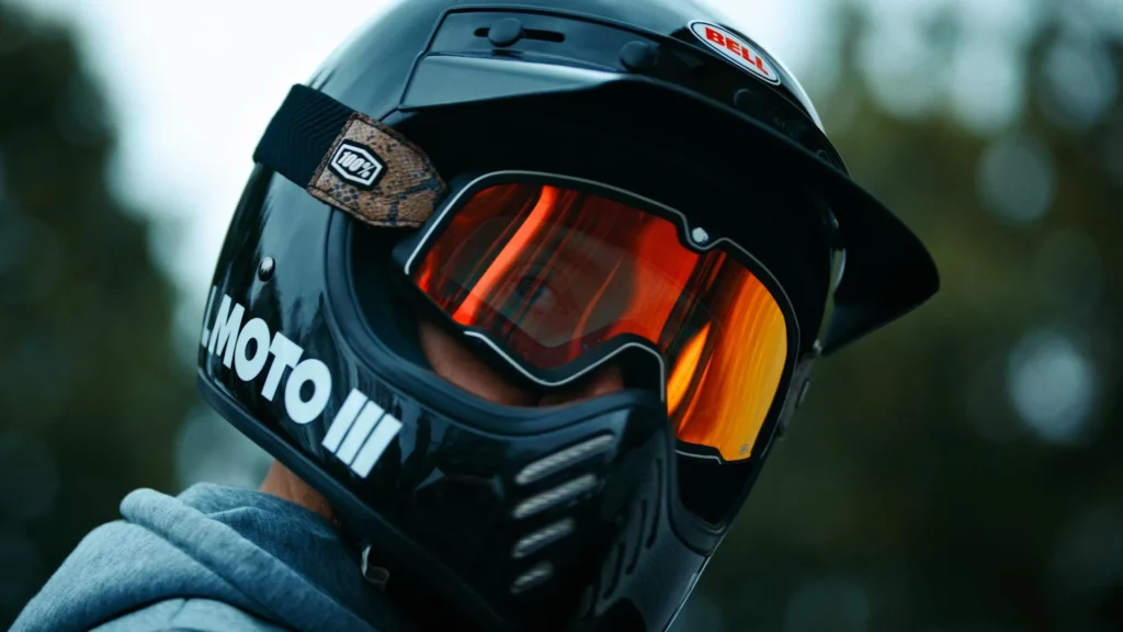 about-slider-motard-casque-route Motard portant un casque et des lunettes teintées, filmé en extérieur dans une ambiance sportive et cinématographique.