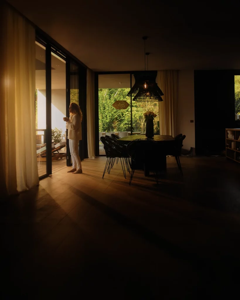 Plan intérieur d’un film de marque avec silhouette près d’une baie vitrée et lumière chaude.