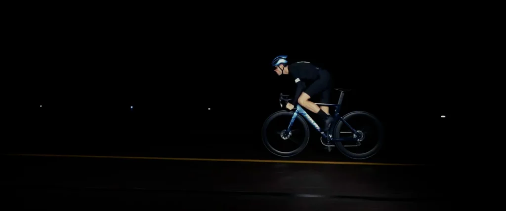Cycliste sur le vélo Adris AXR2 traversant une piste d’aéroport de nuit, entre reflets et lumière rasante.