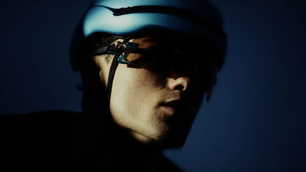 Portrait rapproché d’un cycliste équipé d’un casque dans une lumière bleutée pour la campagne Adris AXR2.
