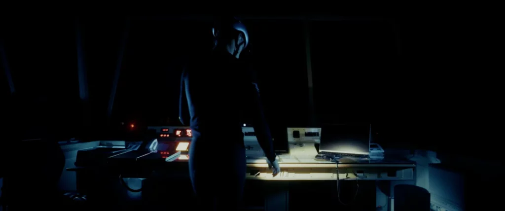 Silhouette dans une tour de contrôle baignée d’une lumière bleutée pour la campagne nocturne Adris AXR2.