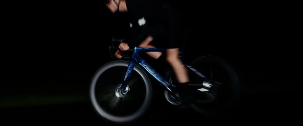 Cycliste sur un vélo Adris AXR2 filmé de profil à grande vitesse dans une nuit presque noire.
