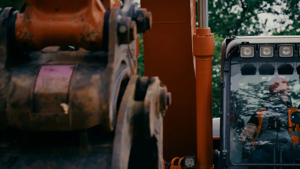 Gros plan sur l’articulation et les éléments mécaniques d’une pelle Hitachi en situation de chantier.