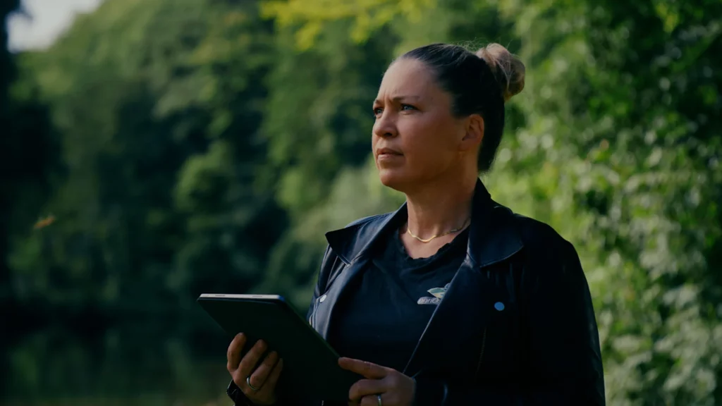 Virginie Labbé consultant une tablette sur le terrain pendant un chantier environnemental.