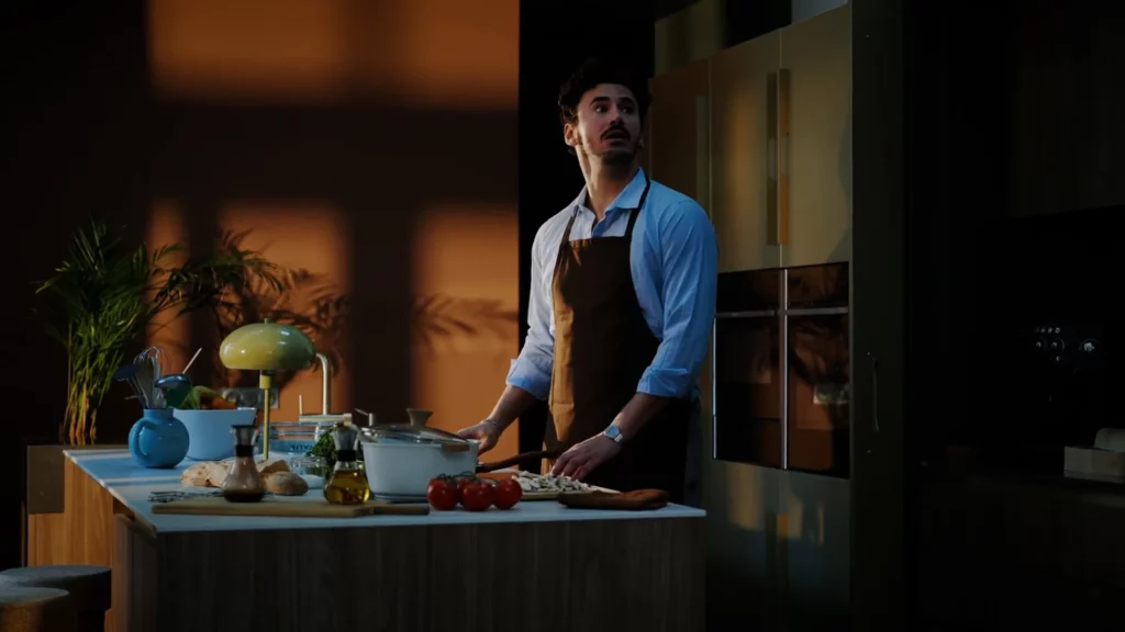 Homme dans une cuisine éclairée chaleureusement, scène de Flexible Contact Center d’Orange Business