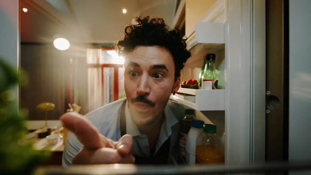 Homme ouvrant un réfrigérateur dans une cuisine, scène de Flexible Contact Center d’Orange Business