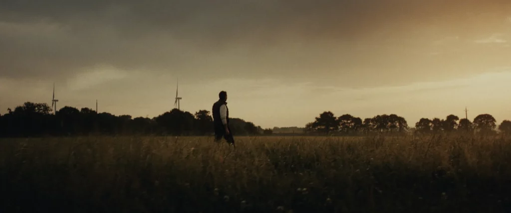 Homme marchant dans un champ au coucher du soleil, séquence terrain du film YDEO Ensemble, formulons votre avenir